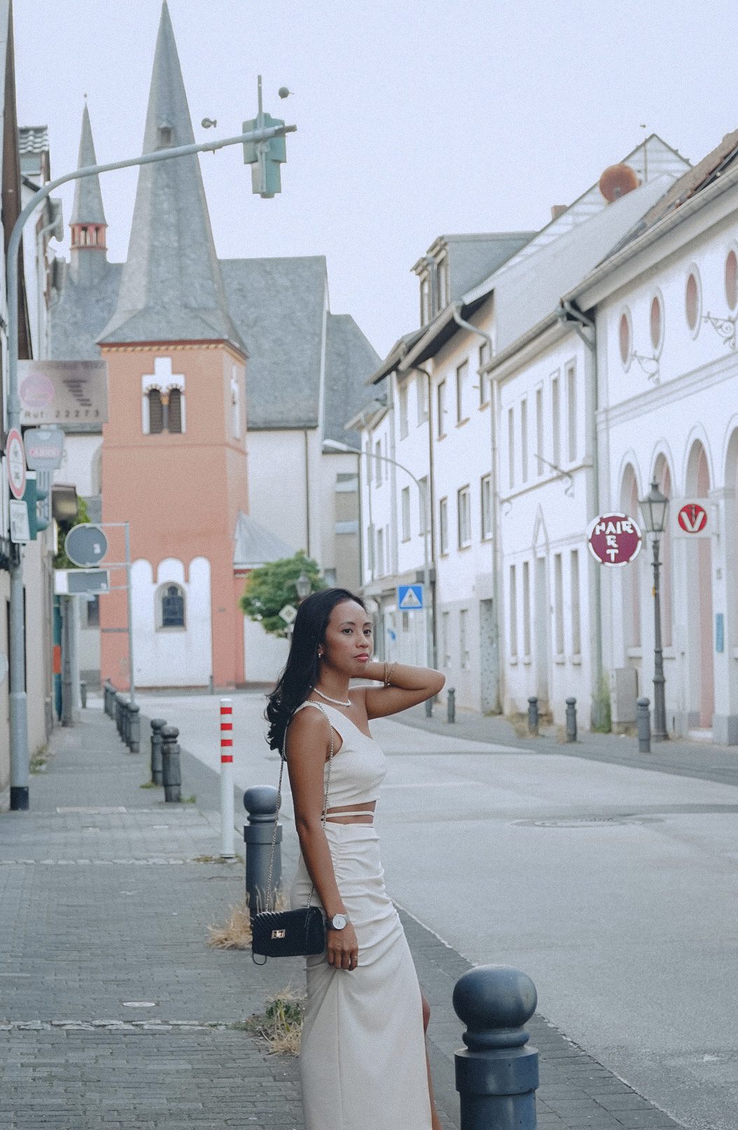 A woman standing in the sidewalk with an architectural background