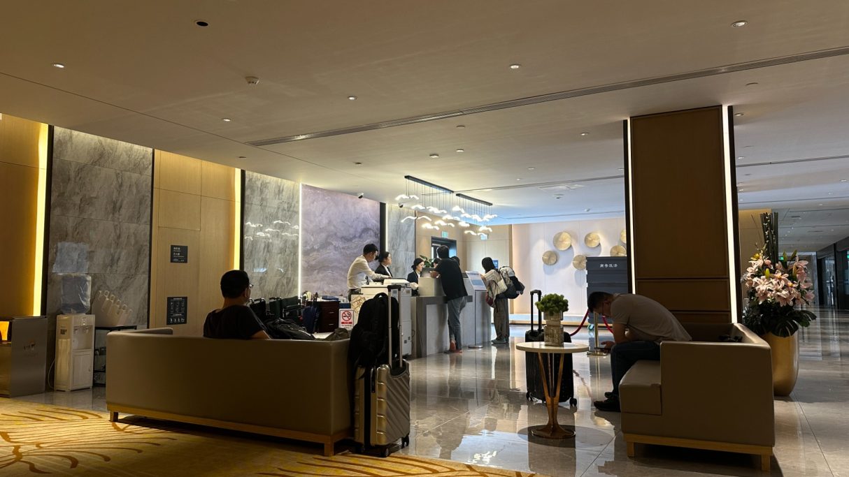 Luxuriöse Hotellobby mit Sitzgelegenheiten und Gästen an der Rezeption.