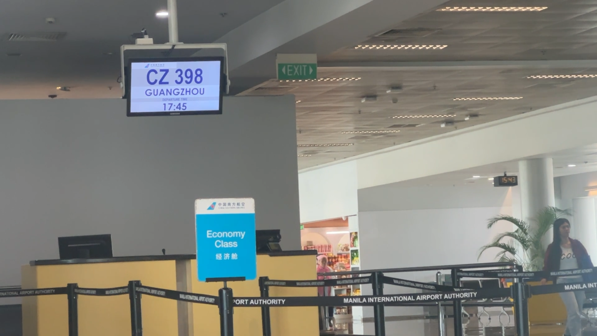 Abflugtafel mit Flug CZ 398, Warteschlange vor dem Schalter im Flughafen.