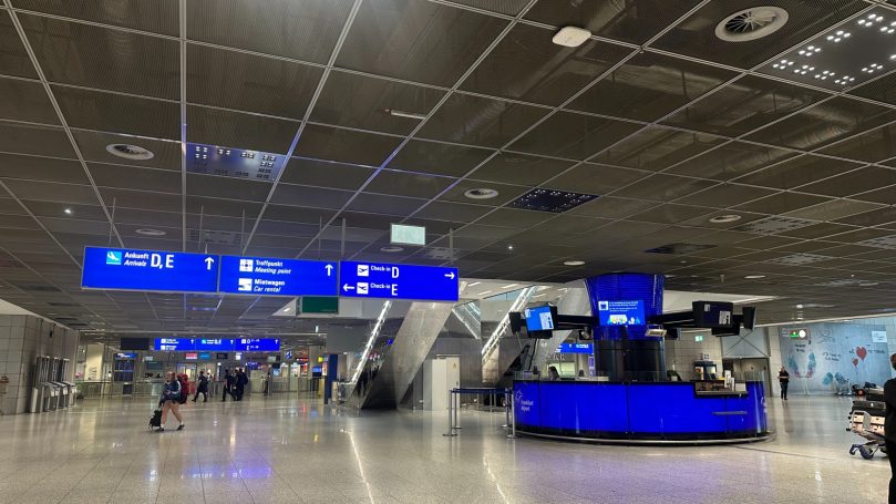 Moderne Flughafenhalle mit Check-in-Schalter und Informationsanzeigen.