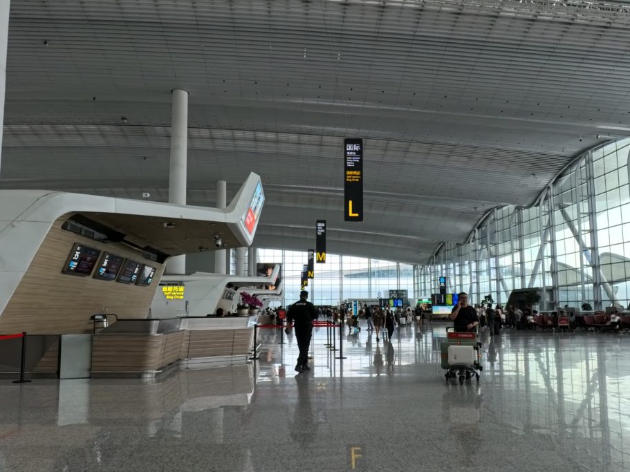 Moderne Flughafenhalle mit Check-in-Schaltern und Reisenden in Bewegung.